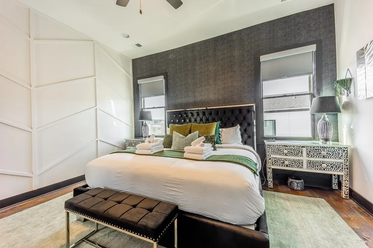 A king-sized bed with plush bedding, decorative pillows, stylish nightstands, and an ornate dresser. The room exudes comfort and elegance, with soft lighting that enhances the serene ambiance, perfect for relaxation and rejuvenation.