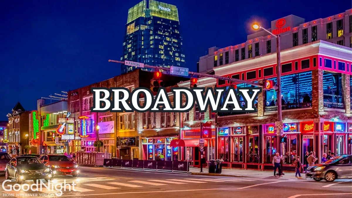 A lively nighttime streetscape featuring neon signs, busy sidewalks filled with people, colorful buildings, and the vibrant energy of Nashville's entertainment district. The scene captures diners, live music venues, and a festive atmosphere—the quintessential Broadway experience.
